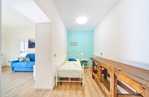 Ein Zimmer mit einem Bett, einem Holztisch, einer blauen Couch und einer hellblauen Wand.