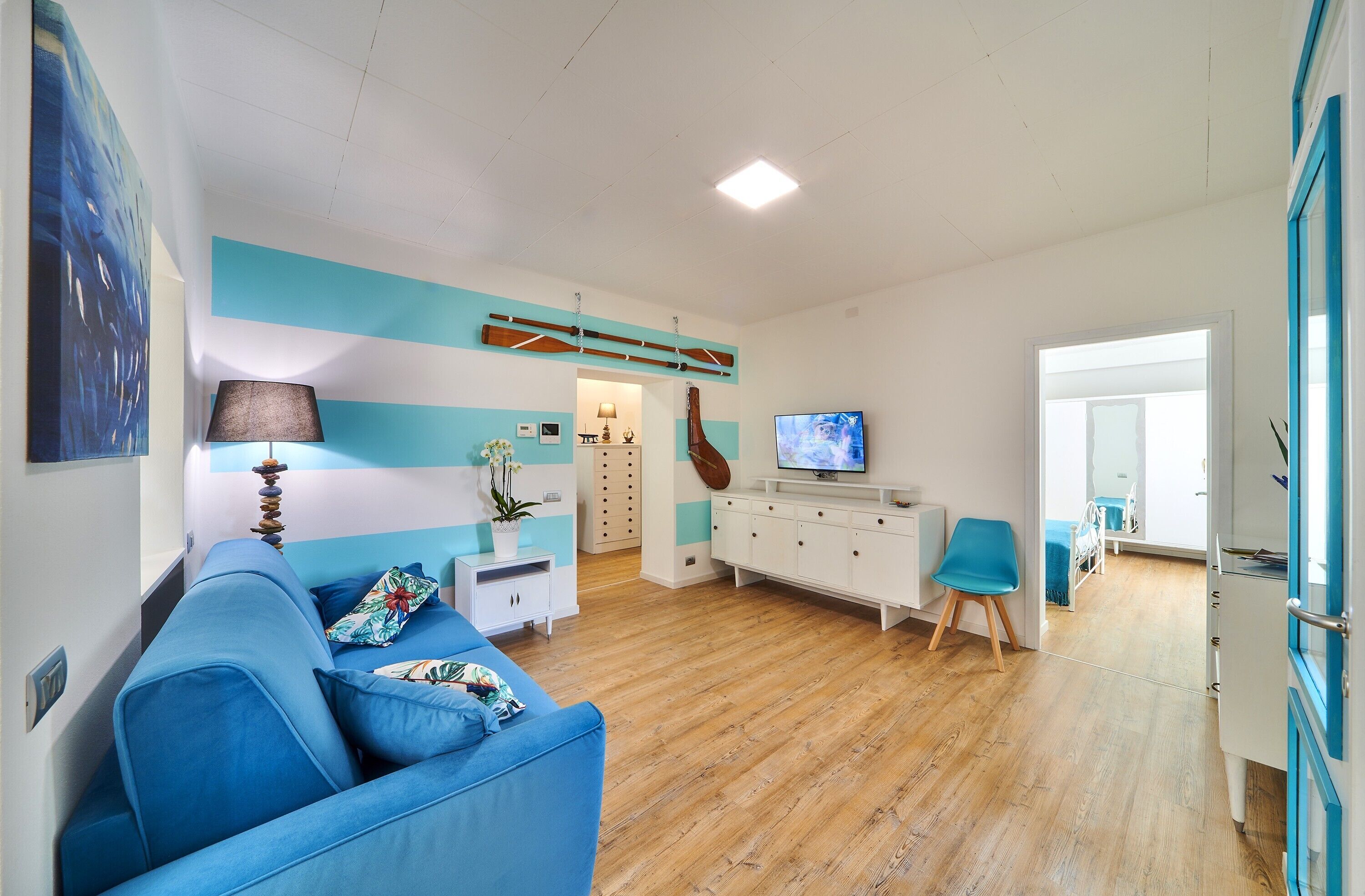 A living room with a blue sofa, a TV, a wooden cabinet, and a guitar.