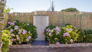 A garden with a bamboo fence, a patterned wall, and hydrangea bushes.