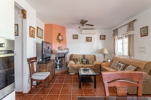 A living room with a sofa, armchair, coffee table, fireplace, and a television. - Vacation Home Casita Puente Viejo with Pool, Wi-Fi, A-C, Terraces & Garden (NERJA)