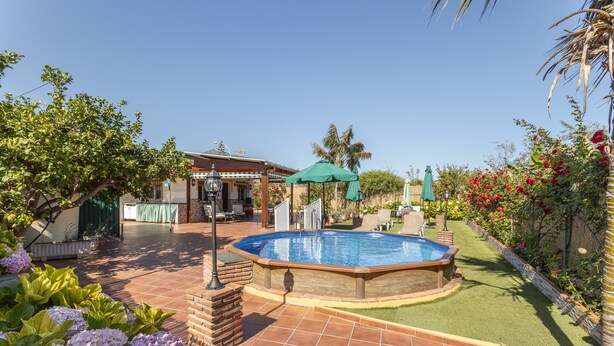 A backyard with a swimming pool, patio furniture, and a house.