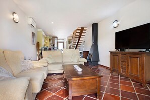A living room with a sofa, a wooden coffee table, a TV, and a fireplace. - Villa Arrancada 7 with Mountain View, Pool, Garden & Wi-Fi (Vale de Margem)
