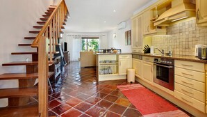 Une cuisine avec un escalier en bois, un sol carrelé et un tapis rouge.
