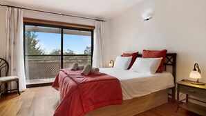 Une chambre à coucher avec un grand lit, une table de chevet, une chaise et une vue sur l’extérieur.