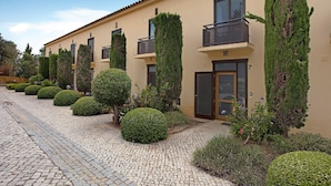 Un bâtiment doté de nombreux balcons, d’une allée pavée et de haies soigneusement taillées.