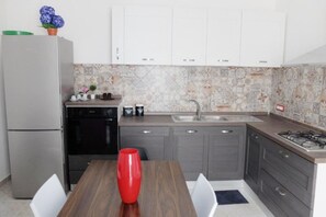 Een koelkast, een oven, een vaatwasser, kookgerei, borden en bestek