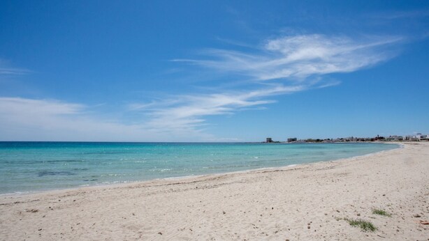 Ein Strand mit klarem, blauem Wasser und sandigem Ufer.