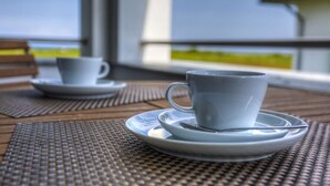 A table with a cup and saucer, a second cup and saucer, and a woven placemat. - Villa Namenlos - Holiday apartment 5 (Börgerende-Rethwisch)