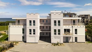 A modern building with a flat roof, multiple balconies, and a clear view of the sea. - Villa Zeitlos - Holiday apartment 1 (Börgerende-Rethwisch)
