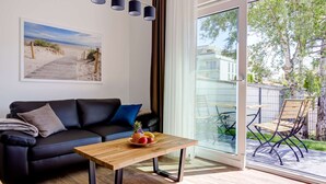En moderne stue med en sort lædersofa, et træbord og et maleri med strandmotiv på væggen.