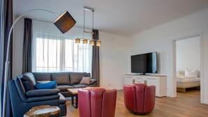 Uma sala de estar moderna com um sofá, pufes vermelhos, uma mesa de centro e uma televisão.