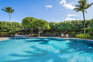 A clear blue pool surrounded by lush greenery and palm trees.