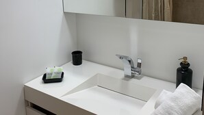 A modern bathroom with a white sink, a mirror, a towel, and a black soap dispenser. - Comfy Pinoche Proche Plage (Saint-Malo)