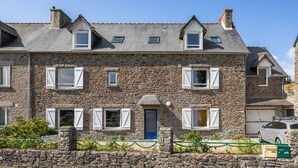 Un edificio de piedra con varias ventanas, una puerta azul y un garaje.