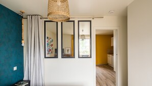 Un dormitorio con cama, mesita de noche, espejo y lámpara colgante.