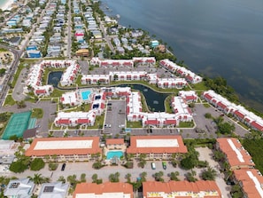 A resort with multiple buildings, a central pool, and a surrounding water body.