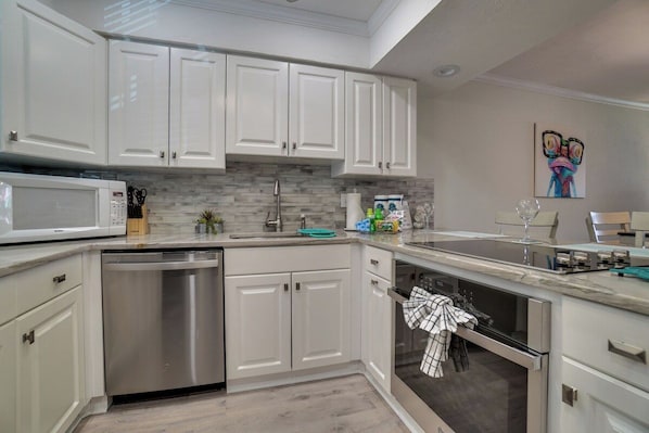 A modern kitchen with white cabinetry, a built-in microwave, and a dishwasher.