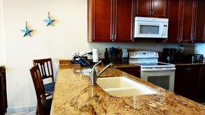 A kitchen with granite countertops, a sink, a microwave, and wooden cabinets.