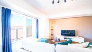 A modern living room with a white sofa, a flat-screen TV, and a floor lamp. - Gree (Otaru)