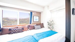 A hotel room with a large bed, a view of the cityscape, and a framed picture on the wall. - Gree (Otaru)