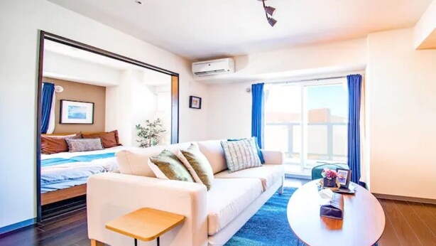 A modern hotel room with a bed, a sofa, a small table, and a window with curtains. - Gree (Otaru)