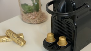 A black espresso machine with two brass cups on a white table. - Jungle Pinoche Proche Plage (Saint-Malo)