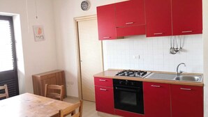 Cuina amb armaris vermells, fogó de gas, forn i rentaplat.