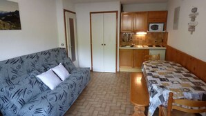 A compact living space with a sofa, a dining table, and a kitchenette.