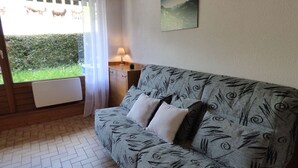 A cozy room with a patterned sofa, a small table, and a window with curtains.