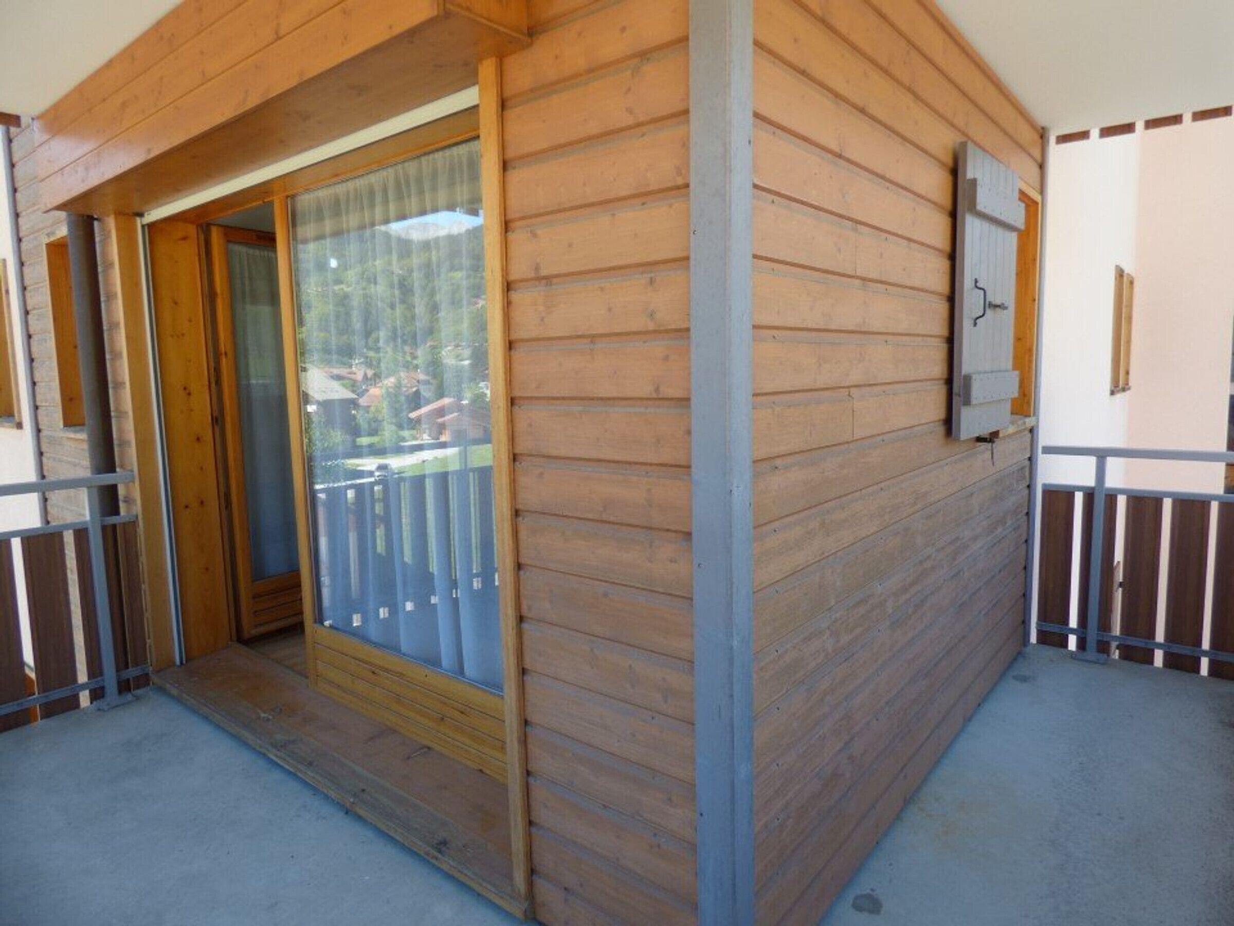 Fachada de madera con puerta corrediza de vidrio que da a un balcón.
