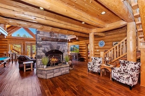 A log cabin interior with a stone fireplace, wooden floors, and a pool table. - Luxury 5 Bedroom! Custom Log Home! A/C! Hot Tub! Pool Table! Foosball! BBQ! (Big Bear City)