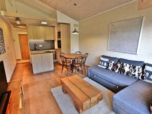 Un espacio habitable compacto con kitchenette, zona de comedor, sofá y mesa de centro.