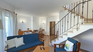 Una sala de estar con un sofá, sillas, una mesa de centro y una escalera.