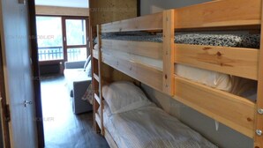 Une chambre avec un lit superposé, un petit canapé et une fenêtre donnant sur un balcon.