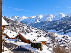 Un pueblo cubierto de nieve con casas de madera y una montaña al fondo.
