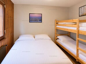 Una habitación con una cama litera, una cama individual y un cuadro en la pared.