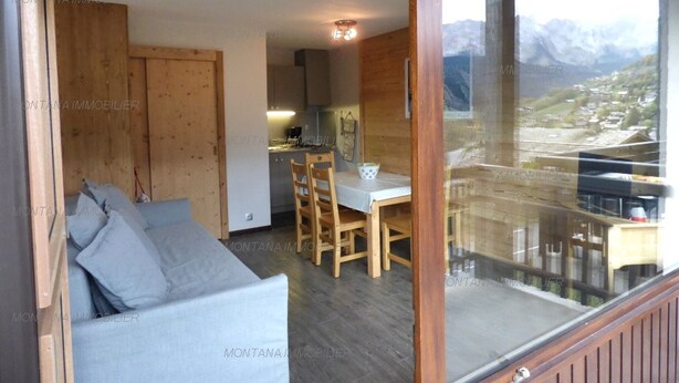 Un intérieur moderne avec un canapé, une table à manger et des chaises, ainsi qu’une grande fenêtre donnant sur une vue imprenable sur les montagnes.