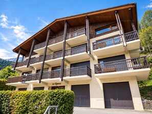A multi-story building with balconies, a sign reading 'Le Choucas,' and a mountainous backdrop. - Renovated studio with south-facing balcony, ideal for 4 people (Le Grand-Bornand)