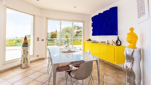 A modern dining area with a glass table, chairs, and a yellow cabinet. - VILLA NICE-GAIRAUT VI4230 BY RIVIERA HOLIDAY HOMES (Niza)