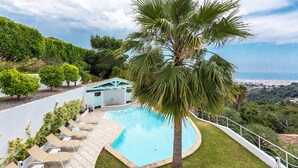 A pool with lounge chairs, a palm tree, and a view of the city. - VILLA NICE-GAIRAUT VI4230 BY RIVIERA HOLIDAY HOMES (Niza)