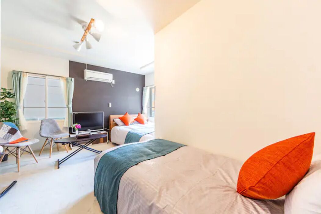 A hotel room with a bed, a desk with a laptop, a chair, and a TV.