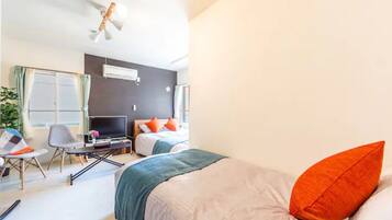 A hotel room with a bed, a desk with a laptop, a chair, and a TV.