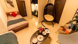 A compact hotel room with a bed, a hanging chair, a dining table set, and a view into the kitchen. - Green (Sapporo)