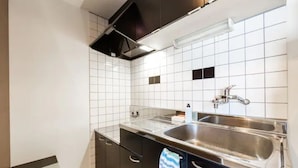 A modern kitchen with white tiled walls, stainless steel sinks, and dark cabinetry. - Green (Sapporo)