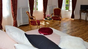 A bedroom with a bed, two chairs, a small table, and a TV.