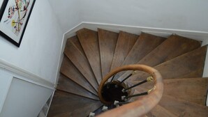A wooden spiral staircase with a handrail, leading upwards.