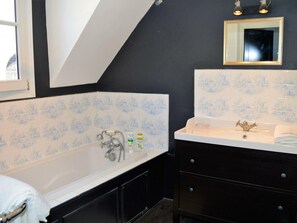 A bathroom with a bathtub, a sink, and a mirror. There are two bottles of lotion on the sink.