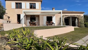 A two-story house with a patio area, a stone structure, and a garden with plants. - An oasis of peace and quite with sea view on Cannes bay (Peymeinade)