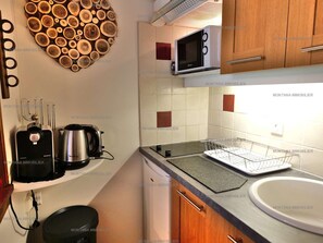 A compact kitchen with a microwave, kettle, and toaster on the countertop.