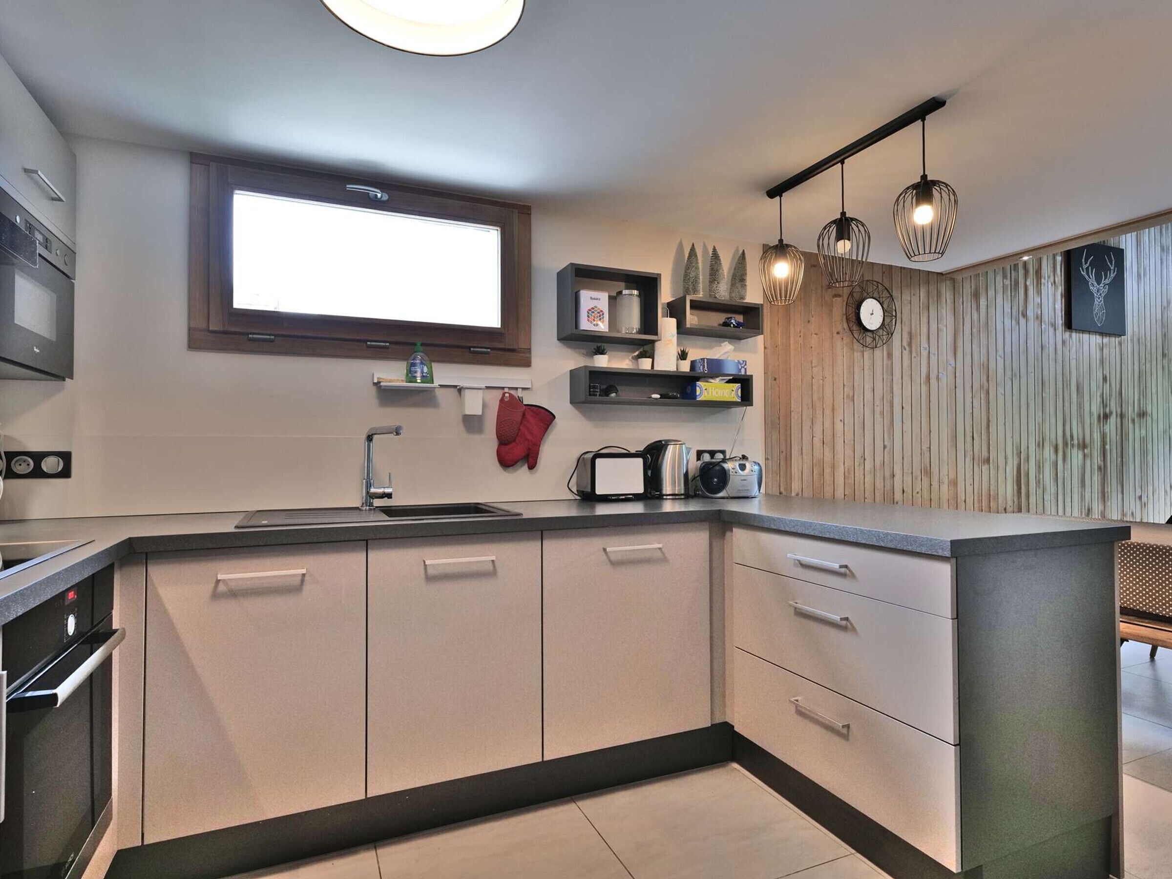 Eine moderne Küche mit Backofen, Spüle und einem Fenster über der Arbeitsfläche.